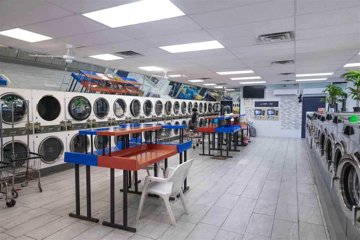 Stacked dryers and folding tables inside Neatly Laundromat, 2333 Hylan Blvd, New Dorp