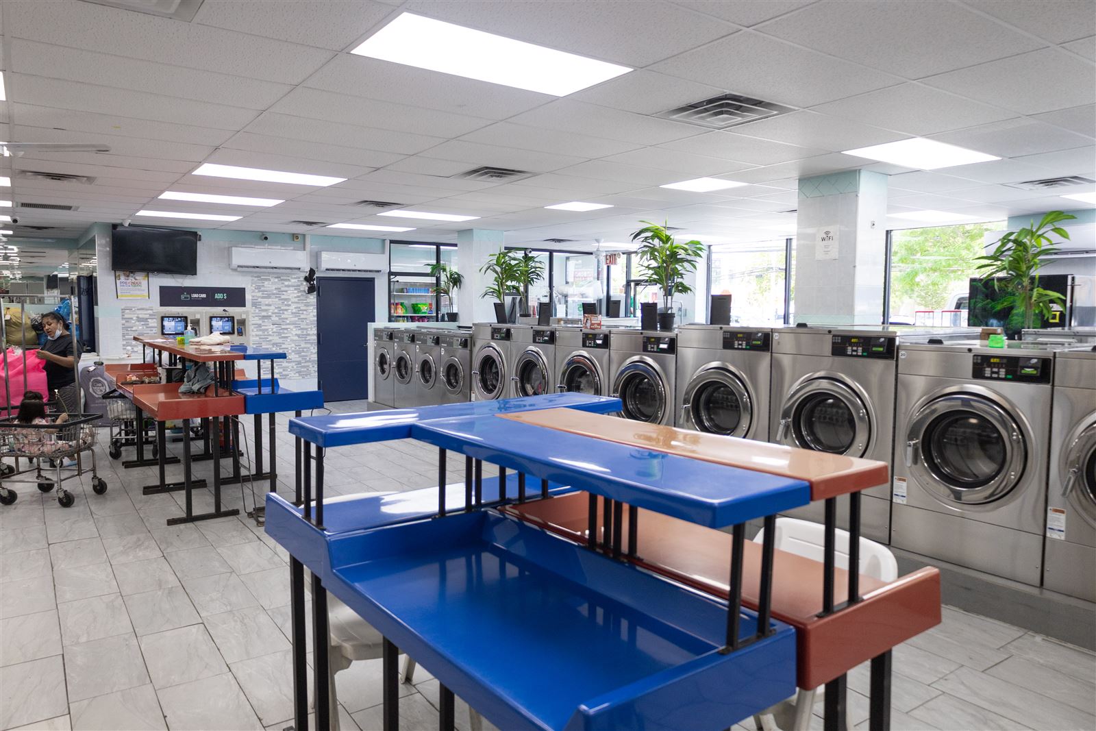 Folding tables, washers and the laundry card reload station inside Neatly, 2333 Hylan Blvd