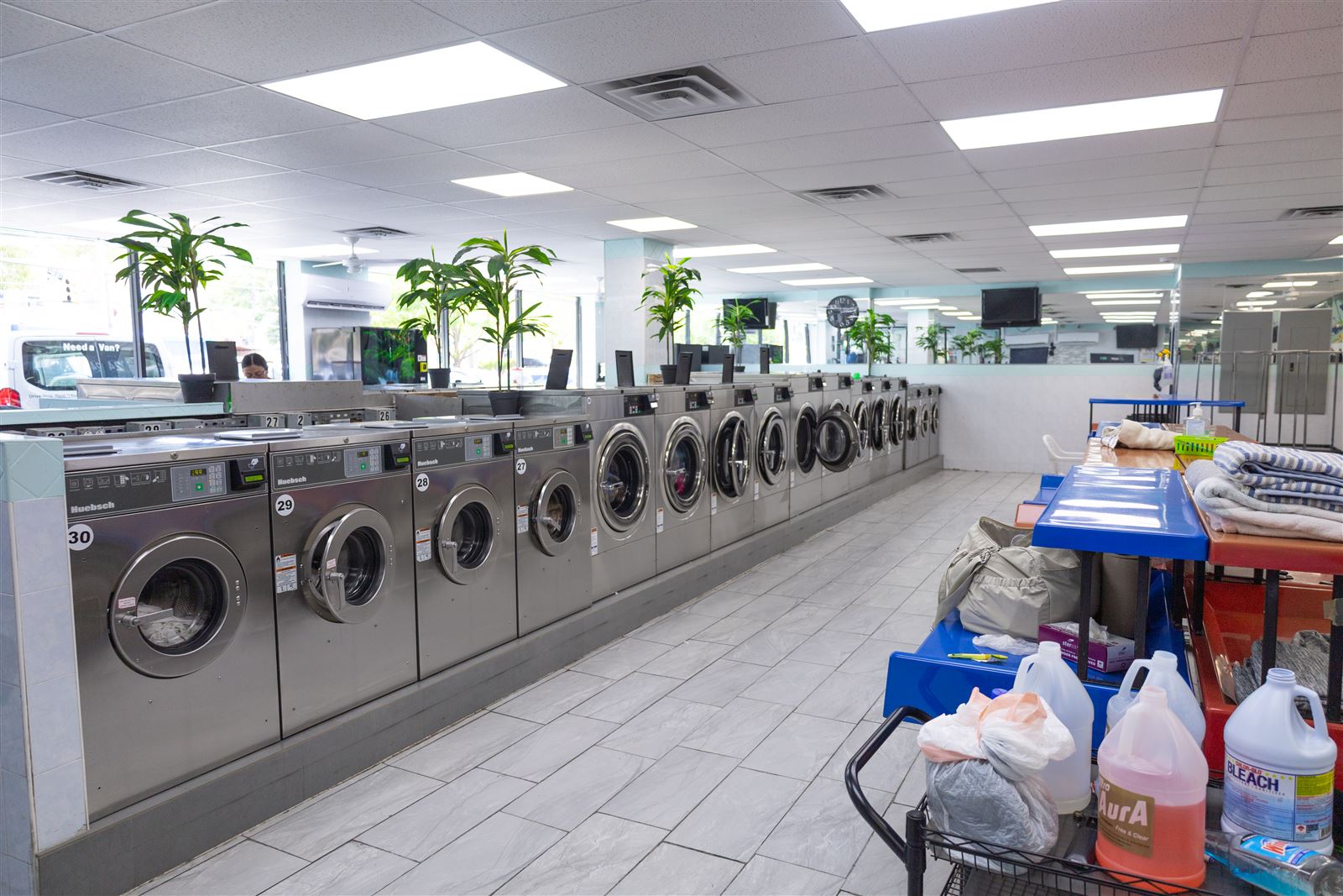 Commercial washers and folded linens at Neatly Laundromat, capacity for business laundry
