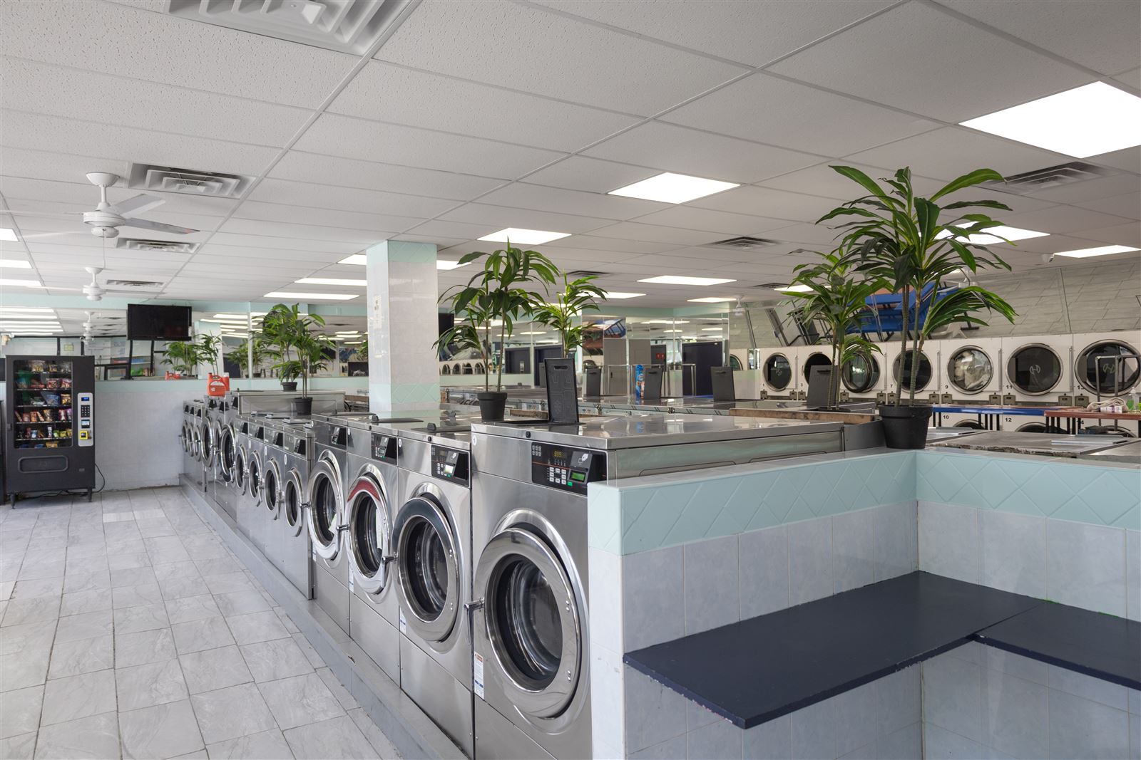 Row of stainless front-load washers and stacked dryers inside Neatly Laundromat at 2333 Hylan Blvd, Staten Island