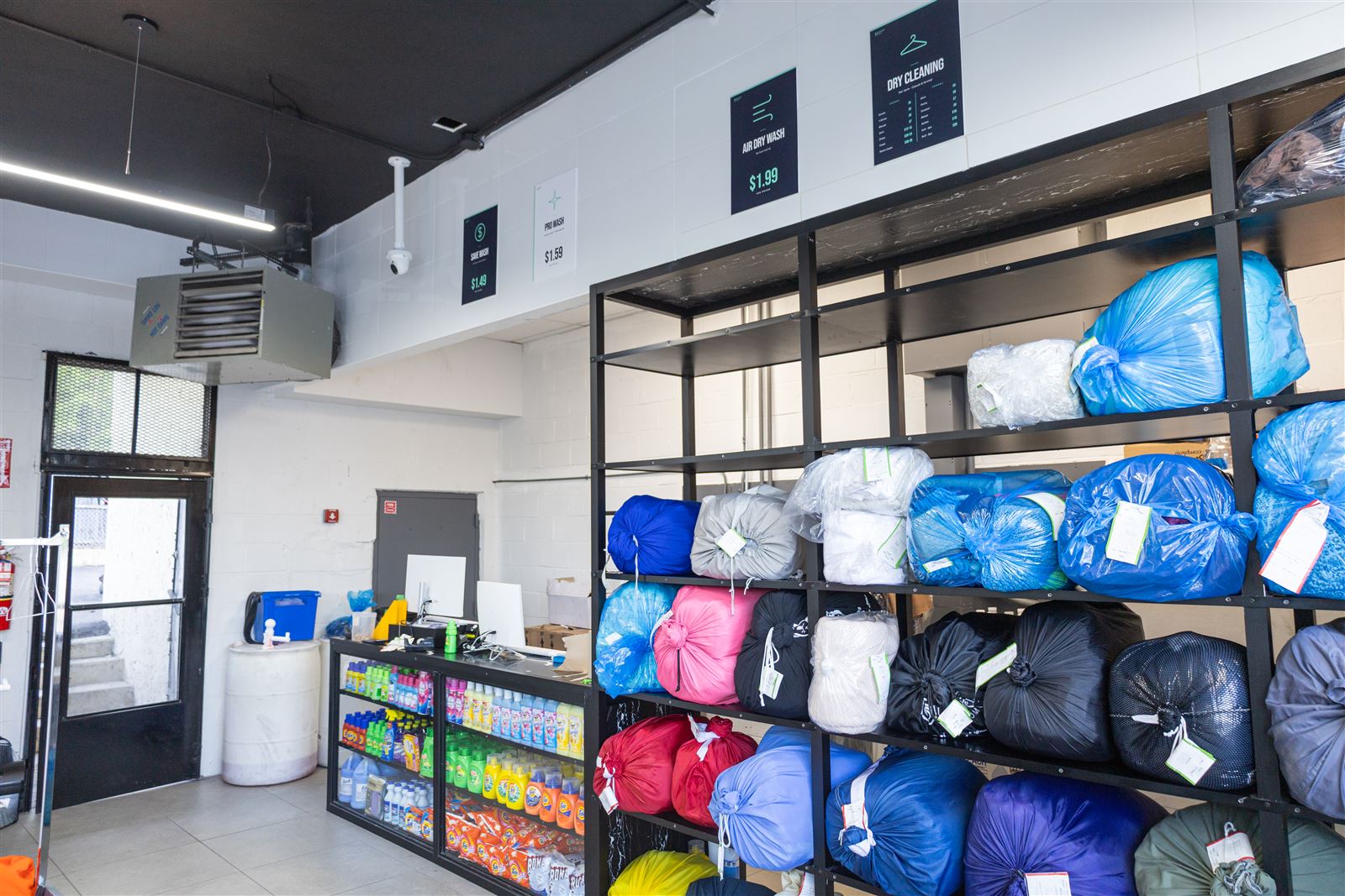 Tagged drop-off laundry bags on the ready shelf waiting for customer pickup at Neatly